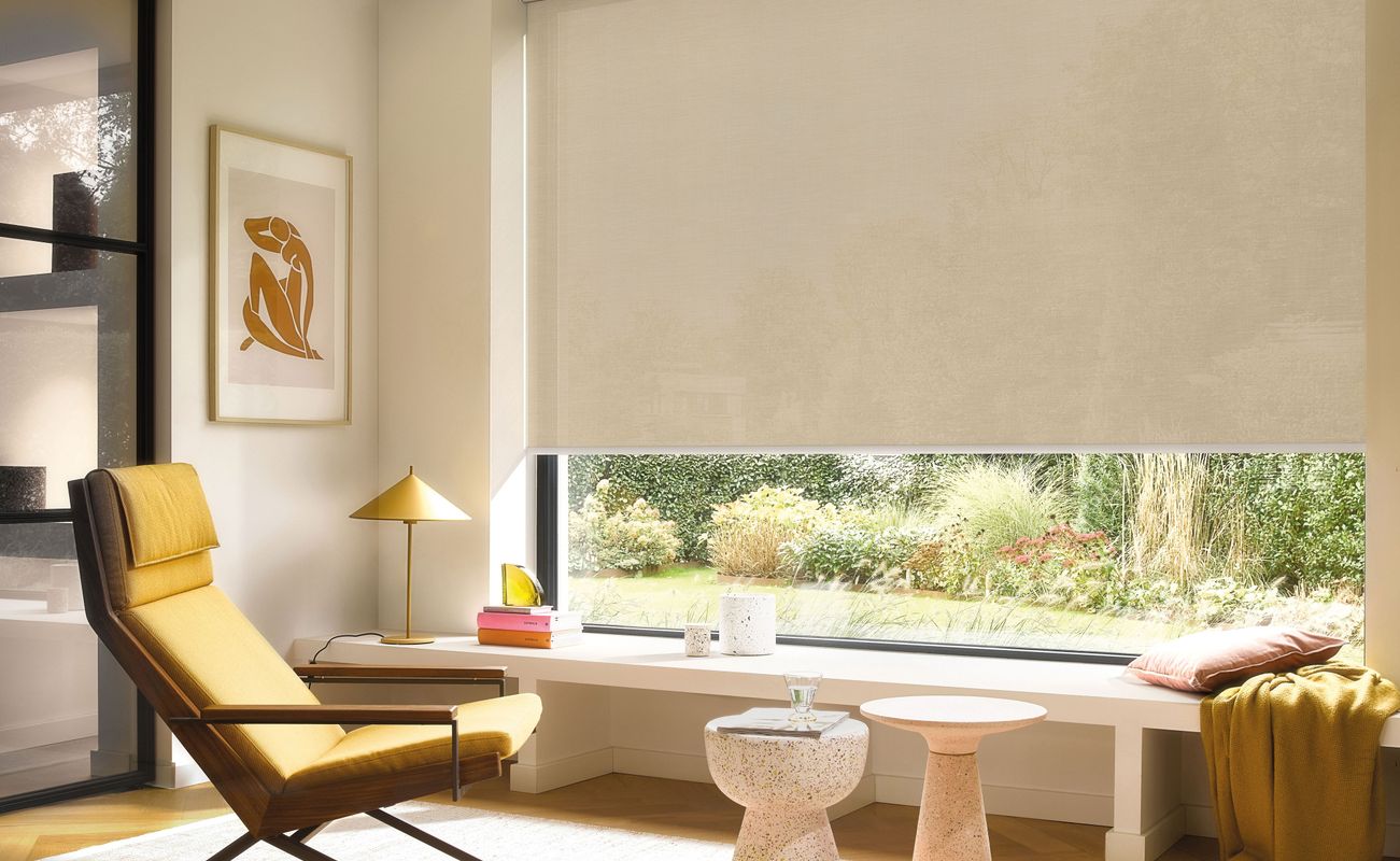 Ein helles Wohnzimmer mit einem gelben Sessel, einem kleinen Tisch und einer großen Fensterbank. Im Hintergrund sind Pflanzen sichtbar.