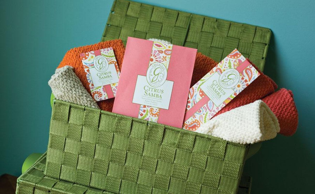 Ein Korb mit bunten Handtüchern in Orange, Weiß und Grün sowie einer pinken Verpackung mit dem Aufdruck 'Citrus Samba'.
