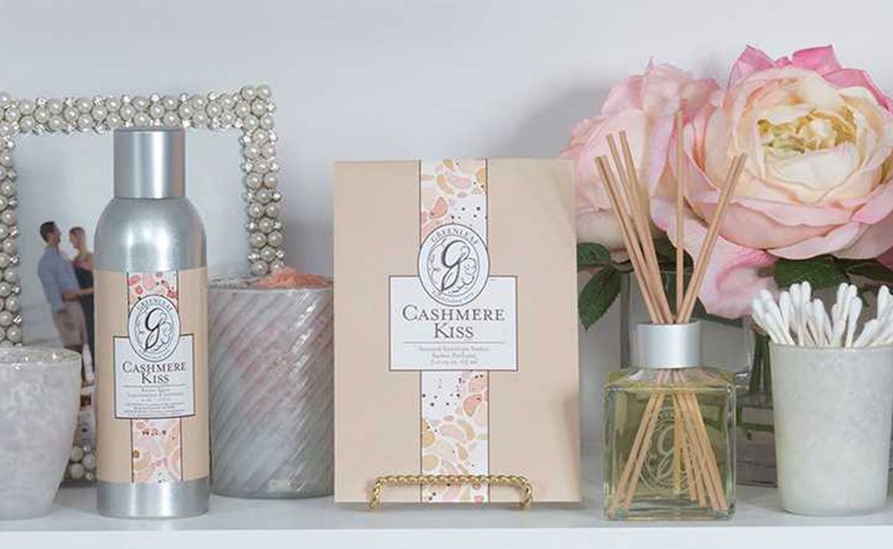 Ein dekorativer Badezimmerbereich mit Handtüchern, einem Foto, einem Duftspender und einem Pflegeprodukt namens Cashmere Kiss.